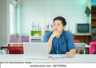 Asian Male University College Student Thinking Looking Up To The Empty Blank Copy Space,Thoughtful Teenage Schoolboy Think About Something While Sitting At Desk In Classroom,education Concept