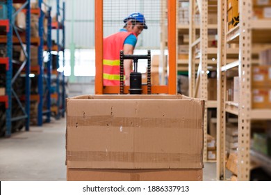 Asian Male Warehouse Worker In Safety Vest And Helmet Driving And Operating On Forklift Truck In The Industry Storage Warehouse With Shelf Pallet Automotive Spare Parts Parcel Blur Background