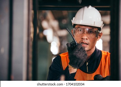 Asian male warehouse worker talking on radio phone or walkie-talkie with colleague driving forklift car in heavy industry manufacturing factory. portrait of men working hard. shipping delivery product