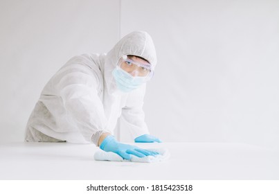 Asian Male Wear PPE Protective Suit Use Alcohol Sanitizer Wipe Cleaning Inside A Building Or Office,To Prevent Spread Of Disease From Crisis Of Coronavirus (COVID‑19) Outbreak.New Normal Concept.