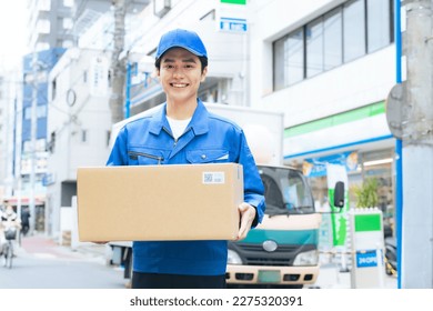 Asian male worker holding a cardboard. Delivery staff. - Powered by Shutterstock