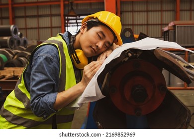 Asian Male Worker Snoozing On Blueprints At Risk Of Accident And Danger Machinery Work Area : Male Worker Sleeps Tired Because Of Little Rest And Too Much Work.
