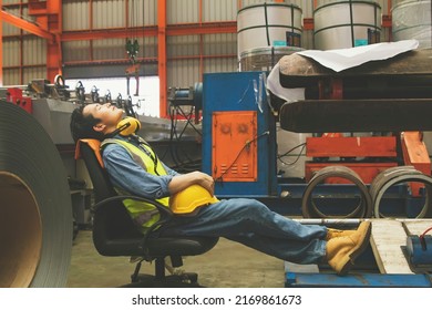 Asian Male Worker Takes Off His Helmet And Sleeps Stretched Chair Taking Daytime Nap During His Break : Factory Worker Working Hard Tired Male Worker Resting Work Area.