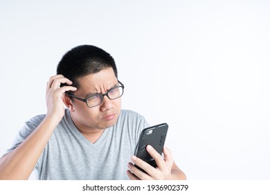 Asian Man About 35 Years Old With Curious And Bad Expression While Looking At Mobile Phone In His Hand