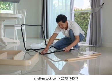 Asian Man Assembling Furniture At Home