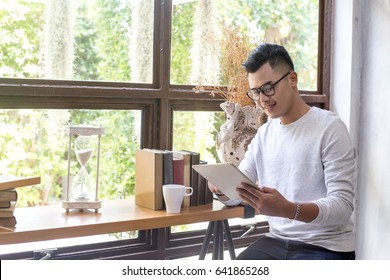 Asian Man With Attractive Smile While Using Tablet At Cafe, 20-30 Year Old.