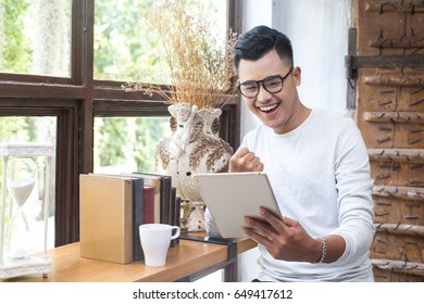 Asian Man With Attractive Smile While Using Tablet At Cafe, 20-30 Year Old.