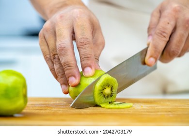 Asian Man Bakery Shop Owner Preparing Bakery In The Kitchen. Adult Male Using Kitchen Knife Cut Fresh Fruit For Making Fruit Tart. Small Business Entrepreneur And Indoor Lifestyle Baking Concept.