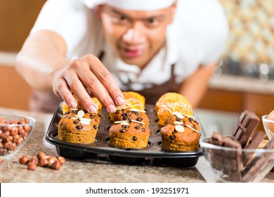 Asian Man Baking Homemade Cup Cake Muffins In His Kitchen For Dessert