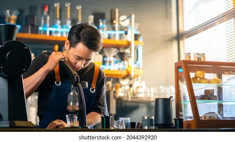 Asian Man Barista Making Hot Espresso Shot From Flair Espresso Coffee Maker At Cafe. Male Coffee Shop Owner Brewing Black Coffee Serving To Customer. Small Business Restaurant Food And Drink Concept