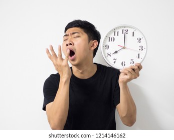 Asian Man Black Shirt Sleepy And Hand Up At The Mouse With Clock  At Left Hand In White Isolated Background,Young Man Yawn And Close The Mouse By Hand Want To Sleep