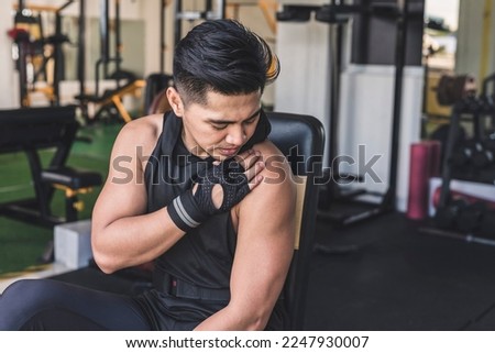 An asian man bothered by a bum shoulder. A possible mild or chronic rotator cuff injury at the gym. Imagine de stoc © 
