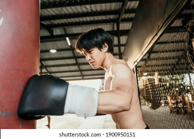 asian man boxer exam exercise hitting punching bag at training camp - Powered by Shutterstock