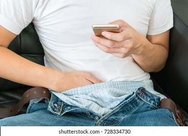 asian man or boy sitting and make a Masturbation during watching online porn or pornographic film movie in mobile phone or smartphone on sofa. focus on smartphone.