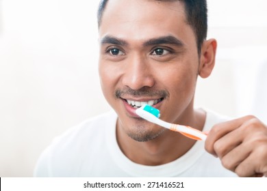 Asian Man Brushing Teeth In The Morning In Bathroom