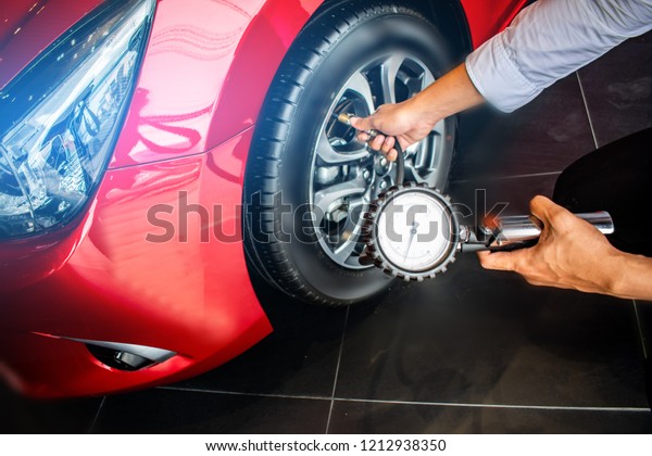 Asian man car inspection Measure quantity Inflated\
Rubber tires\
car.Close up hand holding machine Inflated pressure\
gauge for car tyre\
pressure measurement for automotive, automobile\
image