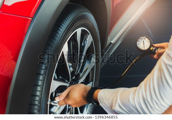 Asian man car inspection Measure quantity\
Inflated Rubber tires car.Close up hand holding machine Inflated\
pressure gauge for car tyre pressure measurement for automotive,\
automobile image\
