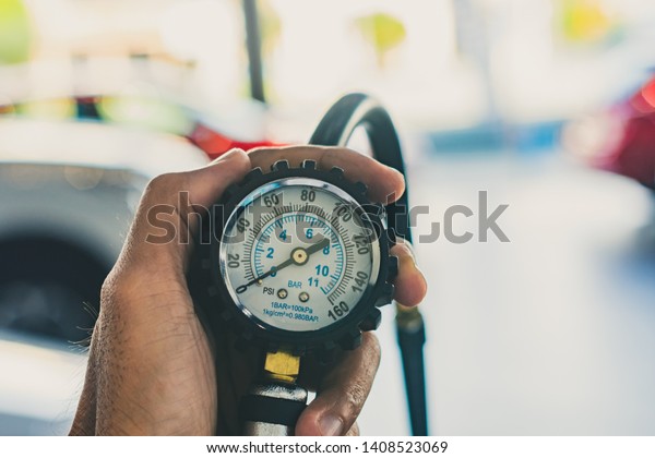 Asian man car inspection Measure quantity\
Inflated Rubber tires car.Close up hand holding machine Inflated\
pressure gauge for car tyre pressure measurement for automotive,\
automobile image\
\
