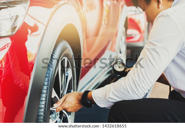 Asian man car inspection Measure quantity\
Inflated Rubber tires car.Close up hand holding machine Inflated\
pressure gauge for car tyre pressure measurement for automotive,\
automobile image\
