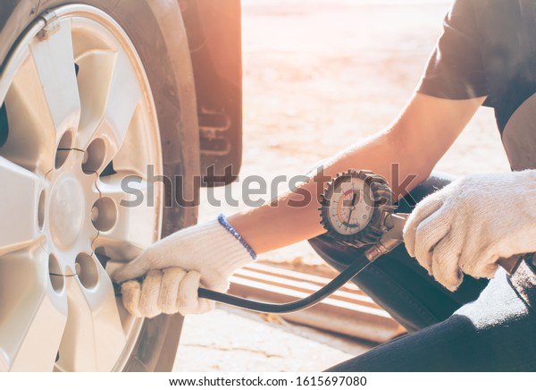 Asian man car inspection Measure quantity Inflated\
Rubber tires car.Close up hand holding machine Inflated pressure\
gauge for car tyre pressure measurement for automotive, automobile\
image