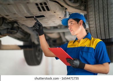 Asian man in car service, repair, maintenance and people concept, happy smiling auto mechanic man or smith with clipboard at workshop