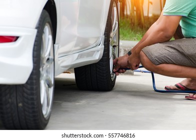 Asian Man Checking Air Pressure And Filling Air In The Tires Of His Car