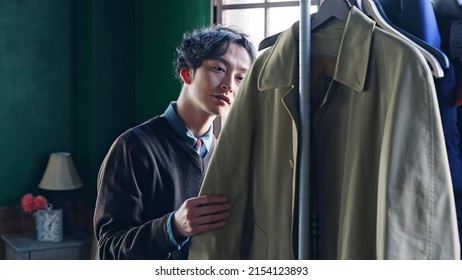 Asian Man Choosing Clothes In Luxury Room.