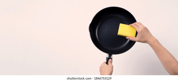 Asian man cleaning the non stick pan with handy dishwashing sponge which yellow color on the soft side and green on hard side for hygiene after cook and white background studio  - Powered by Shutterstock