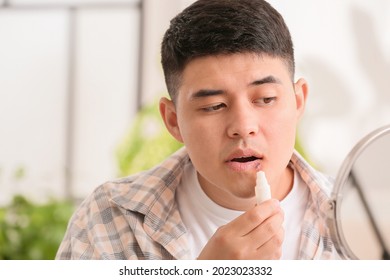 Asian Man With Cold Sore Applying Ointment On His Lips