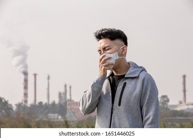 Asian Man Coughs And Wears Protective N95 Mask Because Air Pollution Standing In Front Of Factory