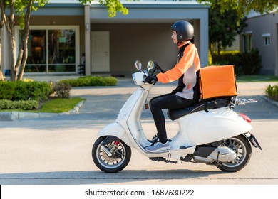 Asian man courier on scooter delivering food in town streets with a hot food delivery from take aways and restaurants to home, express food delivery and shopping online concept.