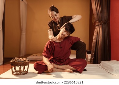 Asian man customer get service thai massage of neck stretching for treat painful from office syndrome with masseur in spa salon. Thai massage with masseur in spa salon.