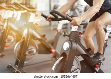 Asian Man Cycling On Bike In Fitness Gym.