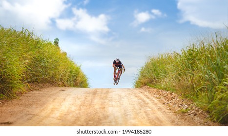 Asian Man Cycling On Gravel Road. He Jumps Action.