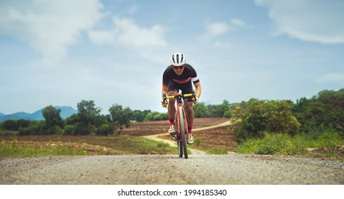 Asian Man Cycling On Gravel Road.