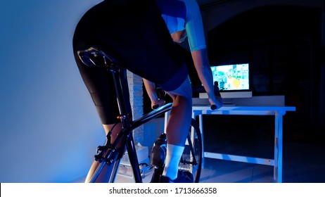Asian man cycling on the machine trainer he is exercising in the home at night.he play online bike game 
