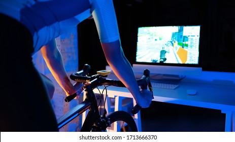 Asian Man Cycling On The Machine Trainer He Is Exercising In The Home At Night.he Play Online Bike Game 