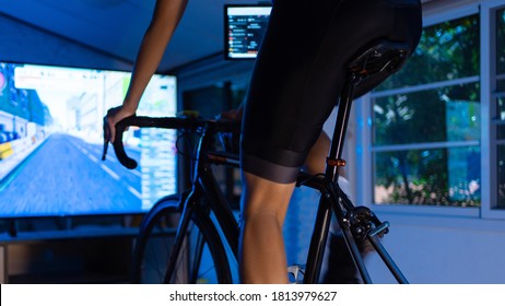 Asian Man Cycling On The Machine Trainer He Is Exercising In The Home At Night.he Play Online Bike Game 