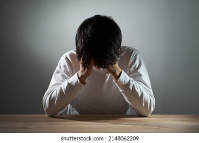 Asian man depressed in a dark room - Shutterstock ID 2148062209