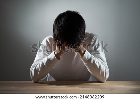 Asian man depressed in a dark room