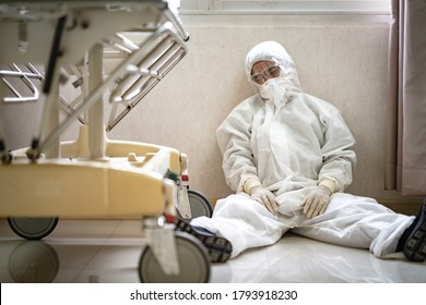 Asian Man Doctor In Protective Hazmat PPE Sad, Tire And Despair. Medical Staff In Clean Suit. Male Practitioner.