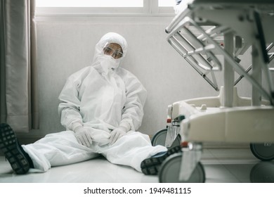 Asian Man Doctor In Protective Hazmat PPE Sad, Tire And Despair. Medical Staff In Clean Suit. Male Practitioner.