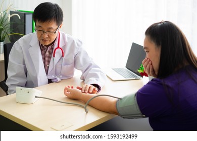 Asian Man Doctor Use Blood Pressure Check And Consult Woman Patient Serious Moment In Desk Hospital