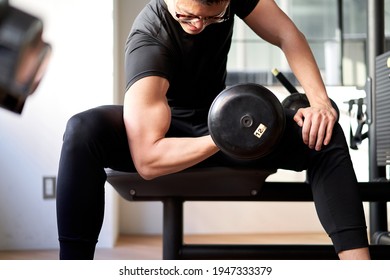 Asian man doing dumbbell curls in a training gym - Powered by Shutterstock