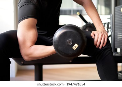 Asian Man Doing Dumbbell Curls In A Training Gym