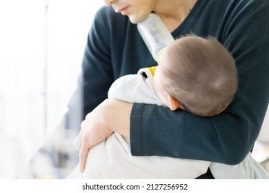 Asian Man Doing Household Chores While Taking Care Of His Baby