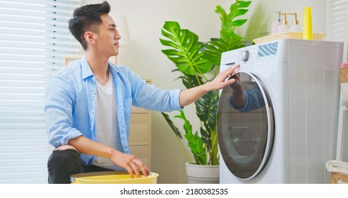 Asian Man Doing Laundry - He Is Setting Washing Machine