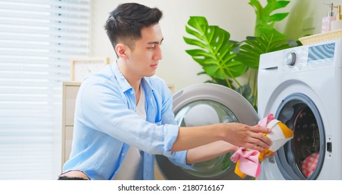 Asian Man Doing Laundry - He Puts All Clothes Into Washing Machine