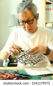 The Asian Man Doing On Plastic Model As His Hobby.