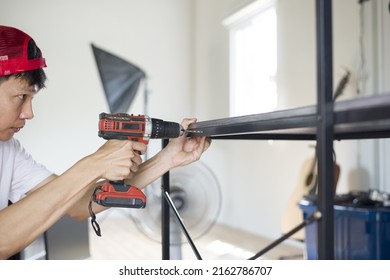 Asian Man Drilling Table With Cordless Drill, Close Up And Copy Space.